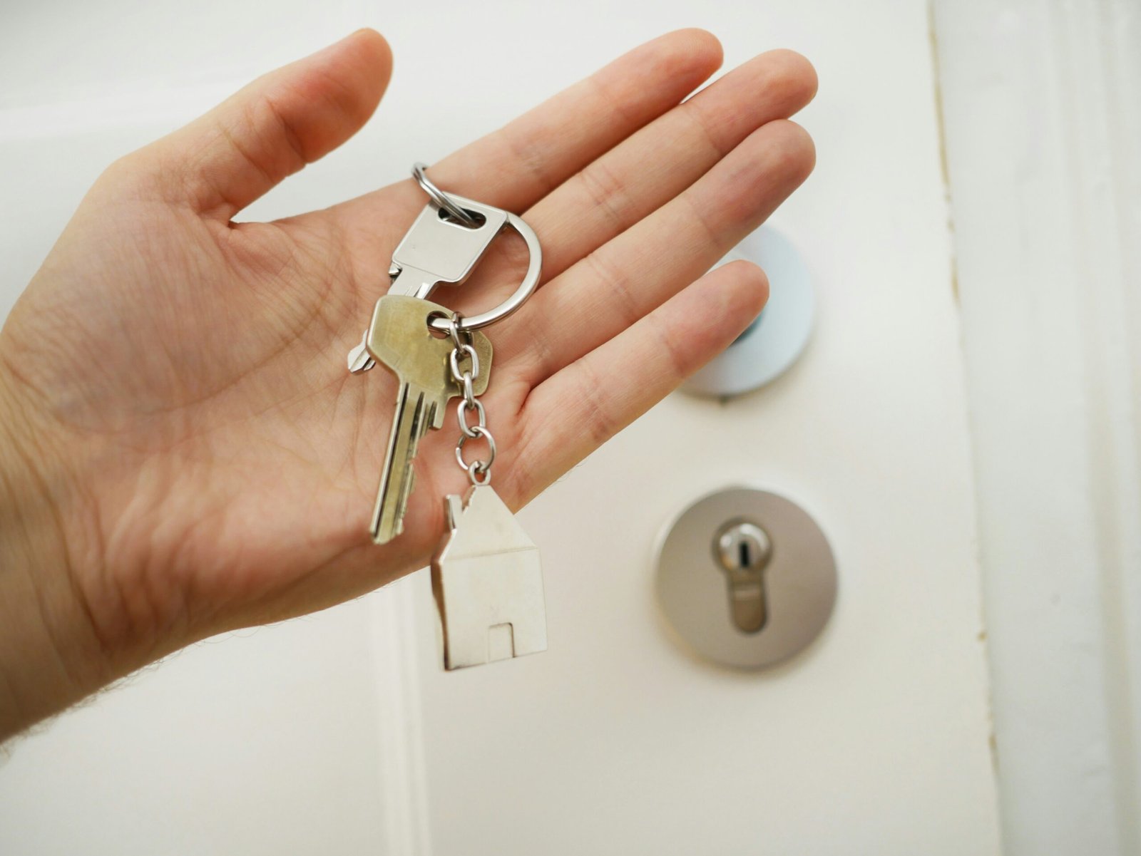 Hand holding house keys with home keychain in front of a door, symbolizing buying a home in Hanover Township NJ
